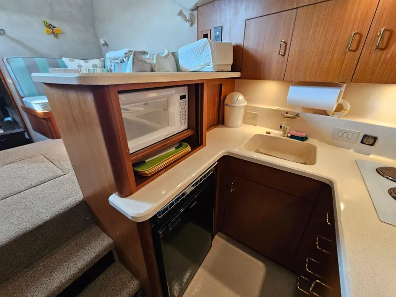 Slide: The Image of Compact kitchen in a 1998 Ocean Yachts 40, featuring a microwave, sink, and wooden cabinetry. - 31