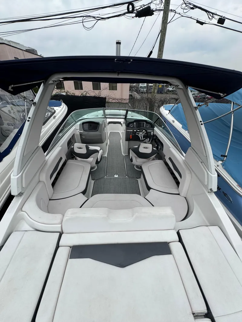 Slide: The Image of 2019 Chaparral 246 SSi boat interior with seating and helm, docked outdoors. - 15