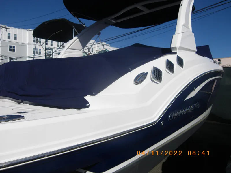Slide: The Image of 2019 Chaparral 246 SSi boat with blue cover, docked outdoors. - 2