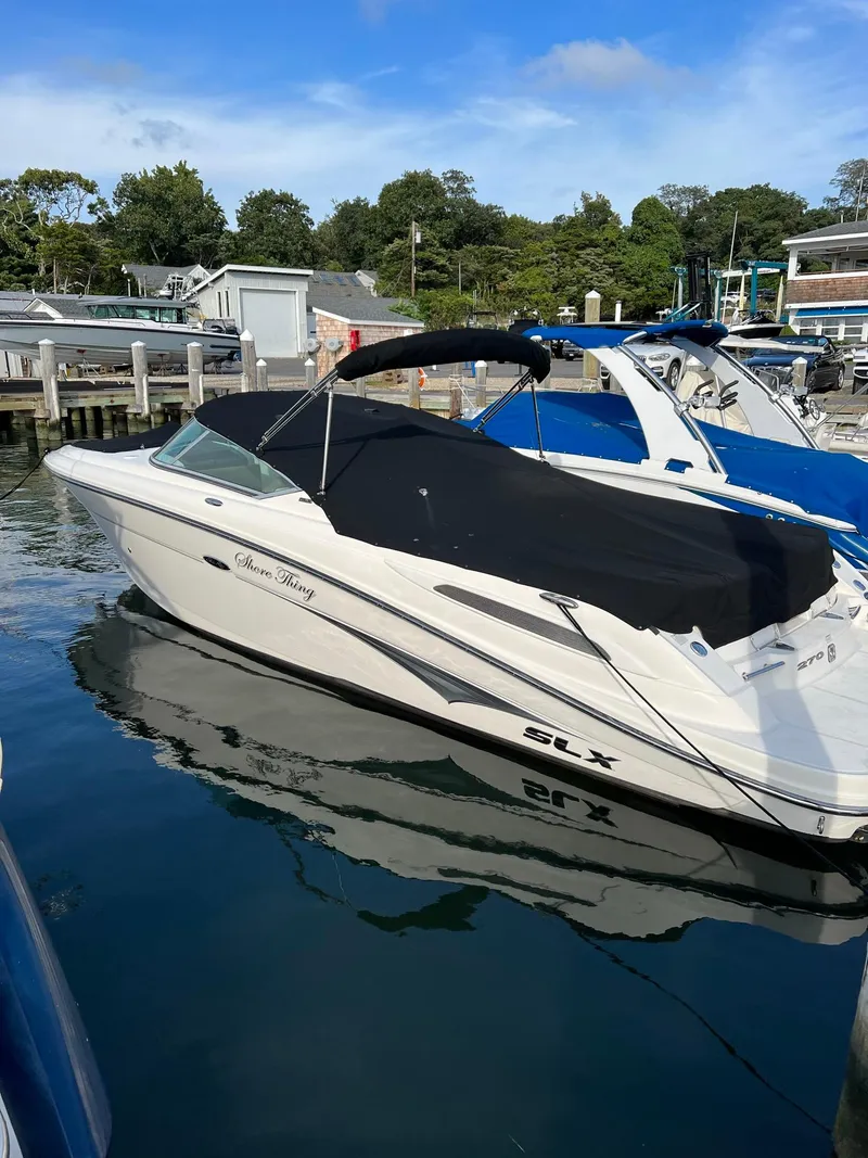 Slide: The Image of 2011 Sea Ray 270 SLX boat docked in a marina with a black cover. - 1