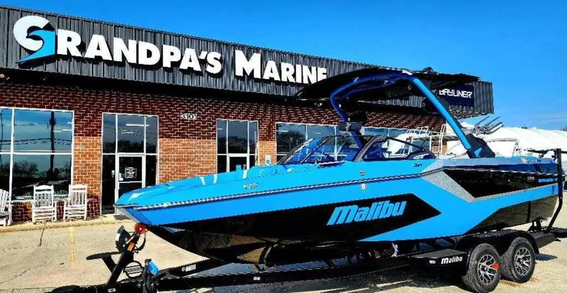 Slide: The Image of 2024 Malibu Wakesetter 23 MXZ boat in blue at Grandpa's Marine dealership. - 1