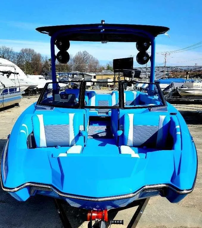 Slide: The Image of 2024 Malibu Wakesetter 23 MXZ boat, vibrant blue, docked, with spacious seating and modern design. - 8
