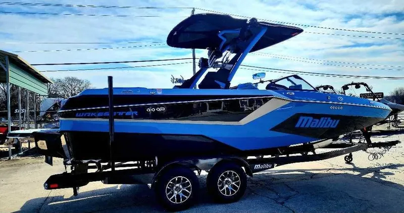 Slide: The Image of 2024 Malibu Wakesetter 23 MXZ boat on trailer, blue and black design. - 9
