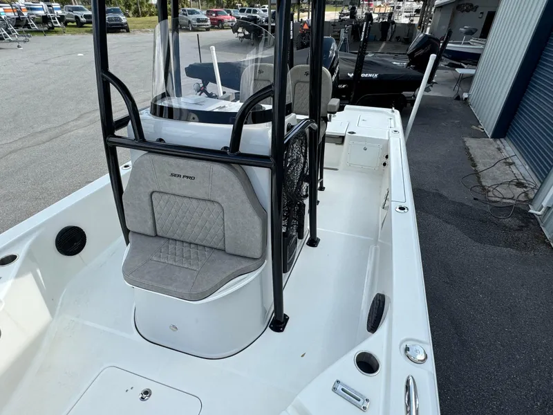 Slide: The Image of 2024 Sea Pro 248 boat interior with seating and console, parked outdoors. - 10