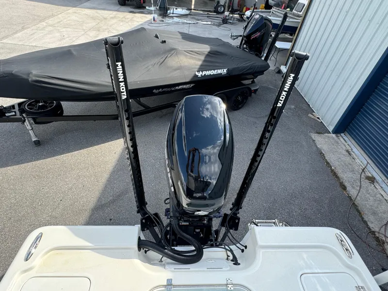 Slide: The Image of 2024 Sea Pro 248 boat with Minn Kota trolling motor, parked near a covered trailer. - 21