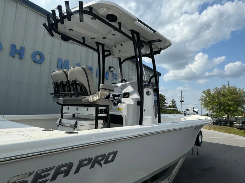 Slide: The Image of 2024 Sea Pro 248 boat with T-top and rod holders, parked outdoors. - 6