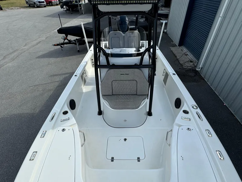 Slide: The Image of 2024 Sea Pro 248 boat, white interior, center console, docked near a blue building. - 9
