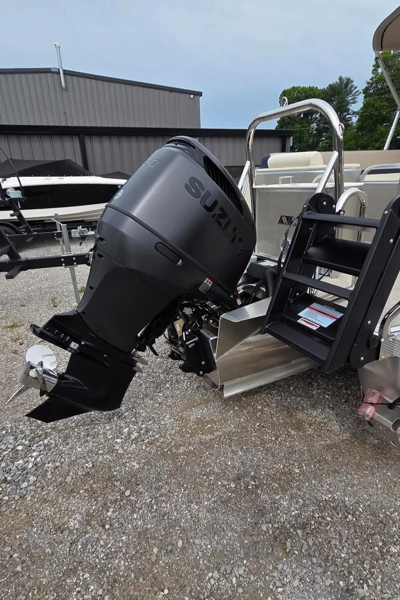 Slide: The Image of 2025 Avalon Platinum Catalina 2585 Quad Lounger with Suzuki outboard motor, parked on gravel. - 10