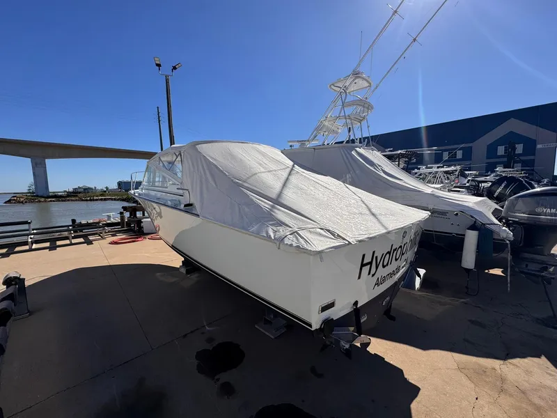 Slide: The Image of 1977 Bertram 28 Moppie boat covered and docked at a marina under clear blue skies. - 11