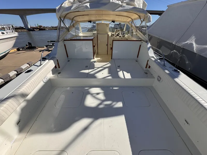 Slide: The Image of 1977 Bertram 28 Moppie boat with spacious deck, docked near a bridge. - 14