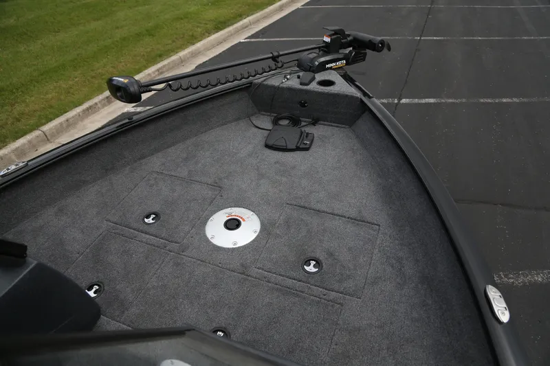 Slide: The Image of 2025 Tracker Pro Guide V-16 WT boat deck with trolling motor in parking lot. - 2