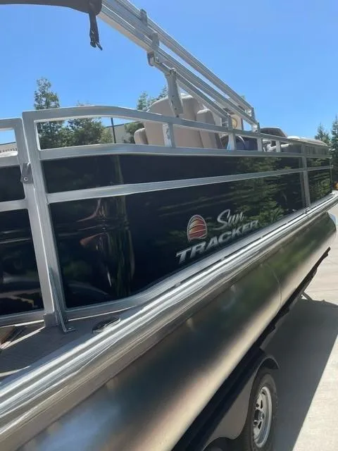 Slide: The Image of 2025 Sun Tracker SportFish 22 DLX pontoon boat, sleek design, parked outdoors. - 2