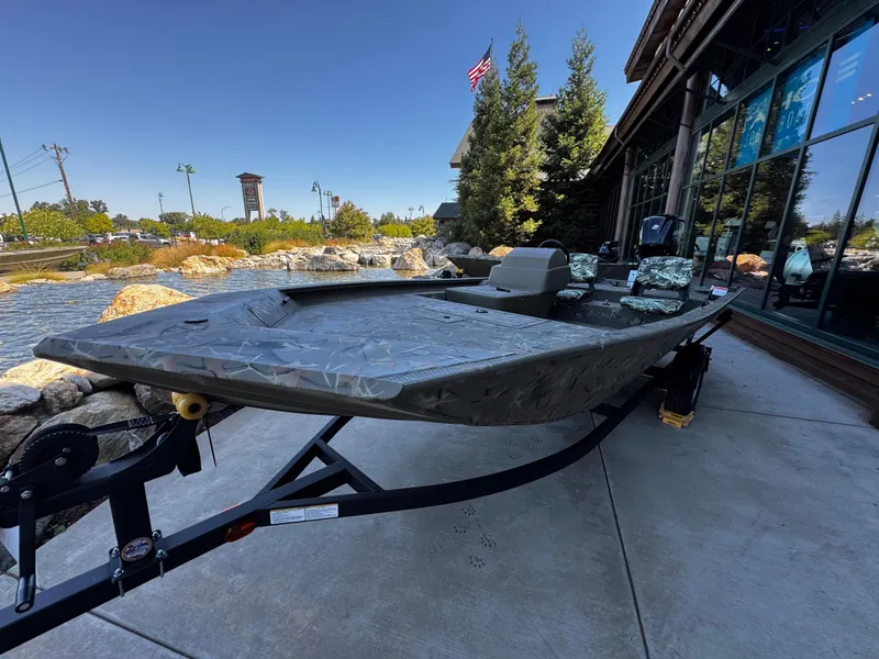 Slide: The Image of 2025 Tracker Grizzly 1754 SC boat displayed outdoors near a building. - 2