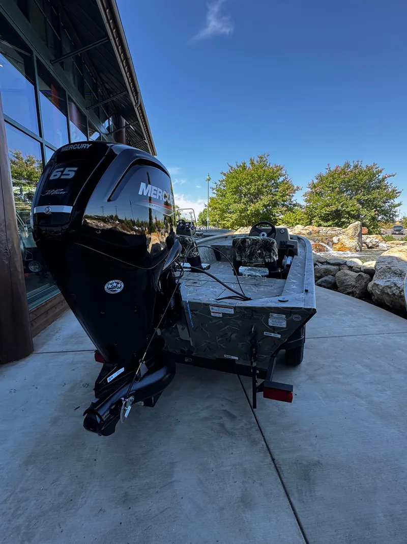 Slide: The Image of 2025 Tracker Grizzly 1754 SC boat with Mercury engine, parked outdoors on a sunny day. - 4
