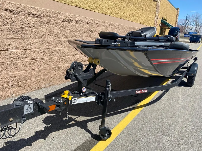 Slide: The Image of 2025 Tracker Bass Tracker Classic XL boat on trailer, parked beside a brick wall. - 2
