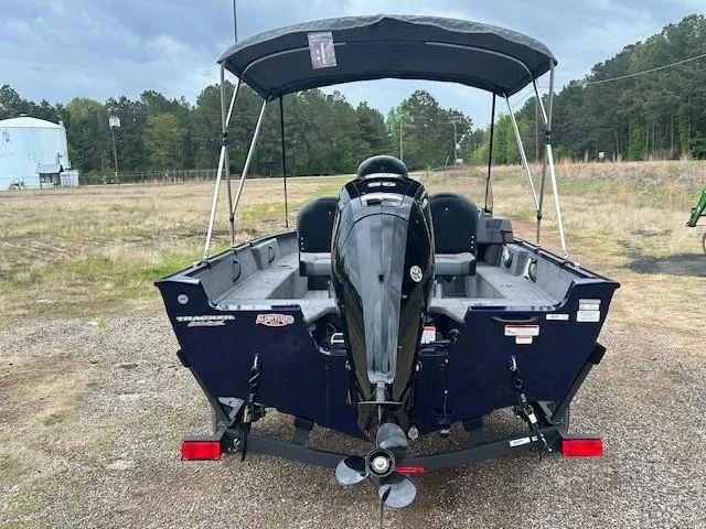 Slide: The Image of 2025 Tracker Pro Guide V-16 SC boat with canopy, parked outdoors. - 6
