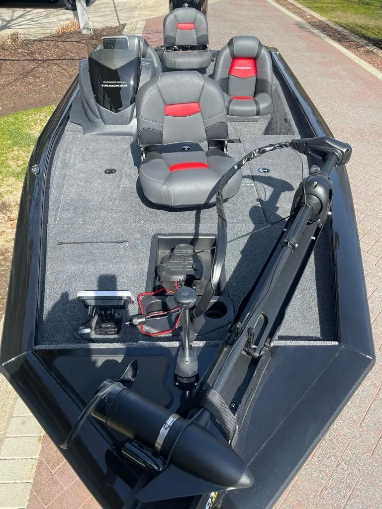 Slide: The Image of 2025 Tracker Pro Team 175 boat with gray and red seating, docked on a sunny day. - 3