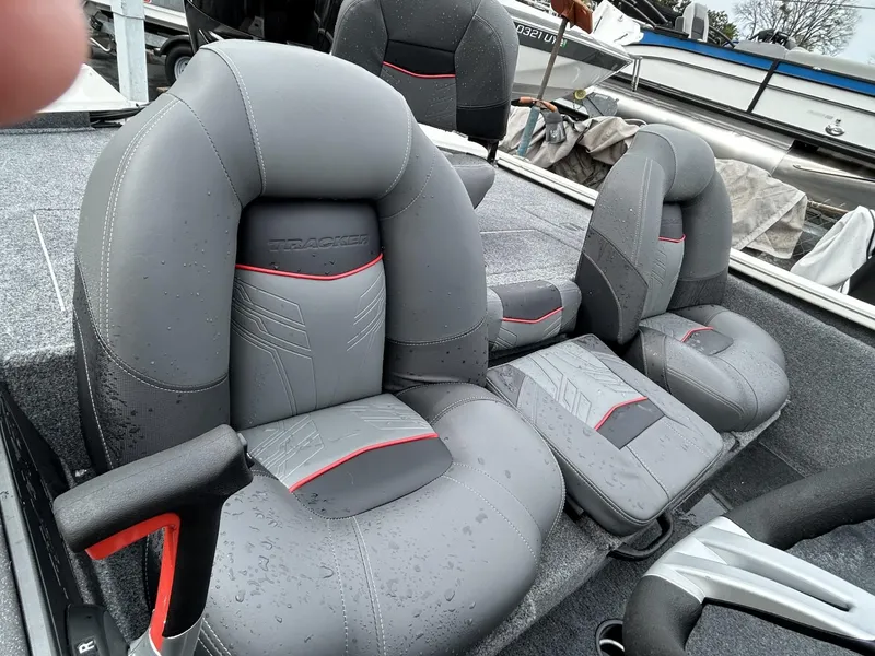Slide: The Image of 2022 Bass Tracker PRO TEAM 175 TXW boat seats, gray with red accents, wet from rain. - 5