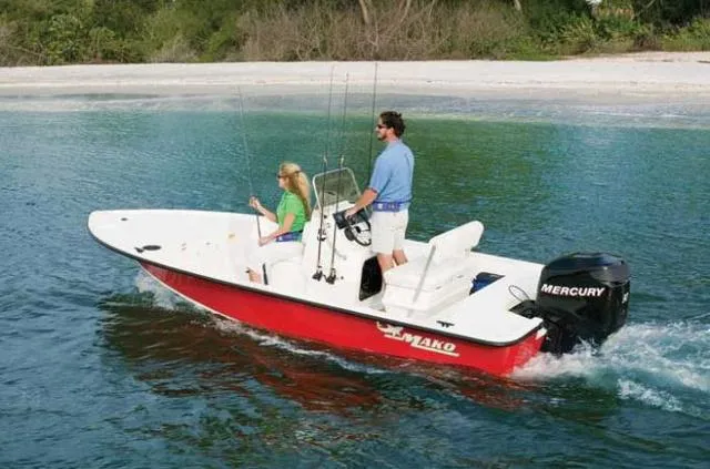 Slide: The Image of Two people on a 2010 Mako 18 Inshore boat cruising near a sandy shore. - 1