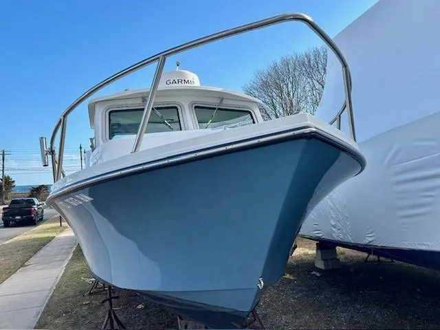 Slide: The Image of 2020 Parker 2320 SL Sport Cabin boat with blue hull, docked outdoors. - 2