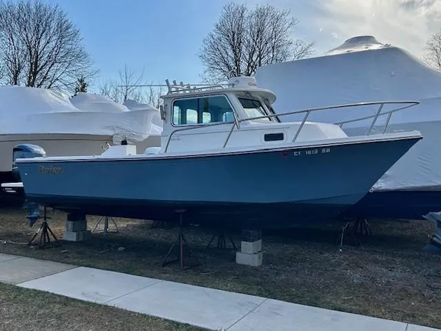 Slide: The Image of 2020 Parker 2320 SL Sport Cabin boat on stands, outdoors, with protective covers nearby. - 3
