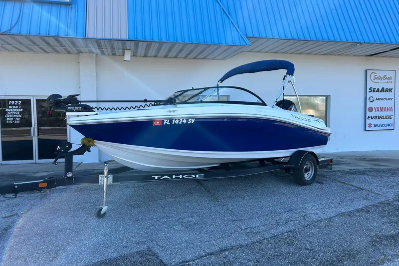 Slide: The Image of 2021 Tahoe 450 TF boat on trailer, parked outside dealership with blue awning. - 5