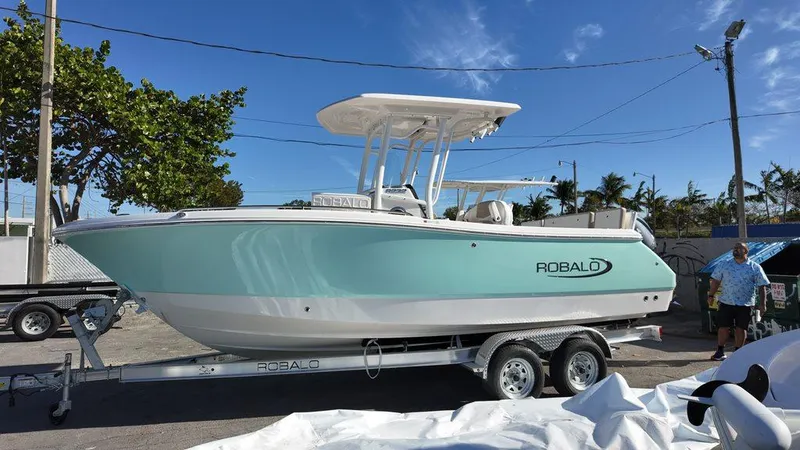 Slide: The Image of 2025 Robalo 232 Explorer boat on trailer, parked outdoors under clear blue sky. - 10