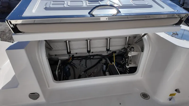 Slide: The Image of 2025 Robalo R250 boat storage compartment with open hatch, showcasing internal components and wiring. - 16