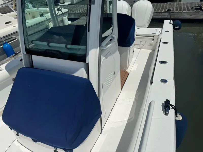 Slide: The Image of 2019 Everglades 273 Center Console boat with blue seat covers, docked at marina. - 10