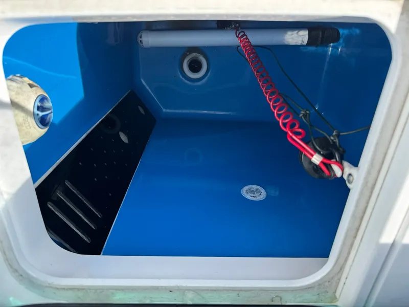 Slide: The Image of 2019 Everglades 273 CC boat storage compartment with blue interior and coiled red cable. - 16
