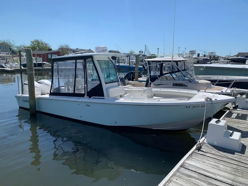 Slide: The Image of 2019 Everglades 273 Center Console boat docked at marina under clear blue sky. - 5