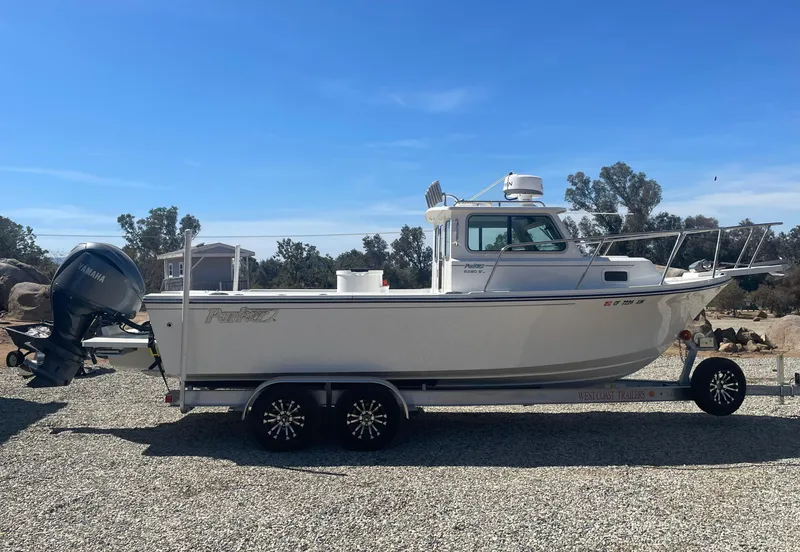 Slide: The Image of 2024 Parker 2320 Sport Cabin boat on trailer, outdoors under clear blue sky. - 4