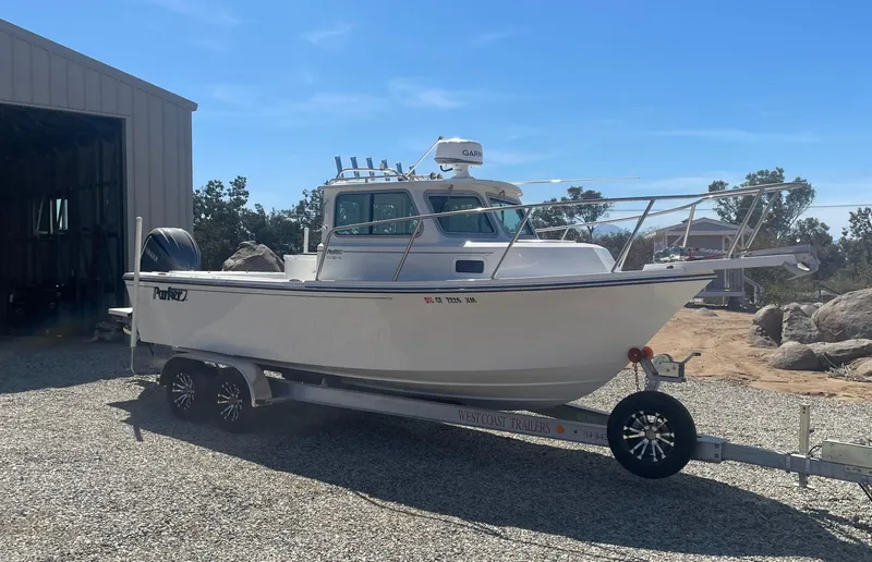 Slide: The Image of 2024 Parker 2320 Sport Cabin boat on trailer, parked outdoors near a building. - 5