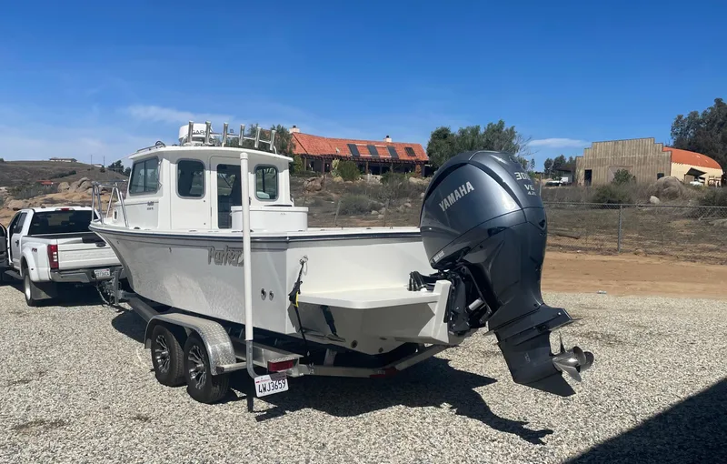 Slide: The Image of 2024 Parker 2320 Sport Cabin boat on trailer, Yamaha engine, parked outdoors. - 8