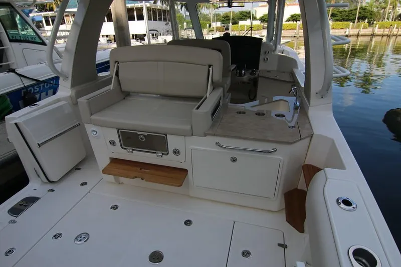 Slide: The Image of 2019 Boston Whaler 350 Realm interior with seating and kitchenette, docked by the water. - 12