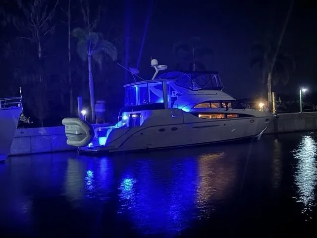 Slide: The Image of 2007 Meridian 459 Motoryacht illuminated with blue lights at night, docked by palm trees. - 38
