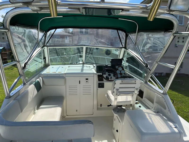 Slide: The Image of 2000 Pursuit 2860 Denali boat interior with seating, steering console, and green canopy. - 19