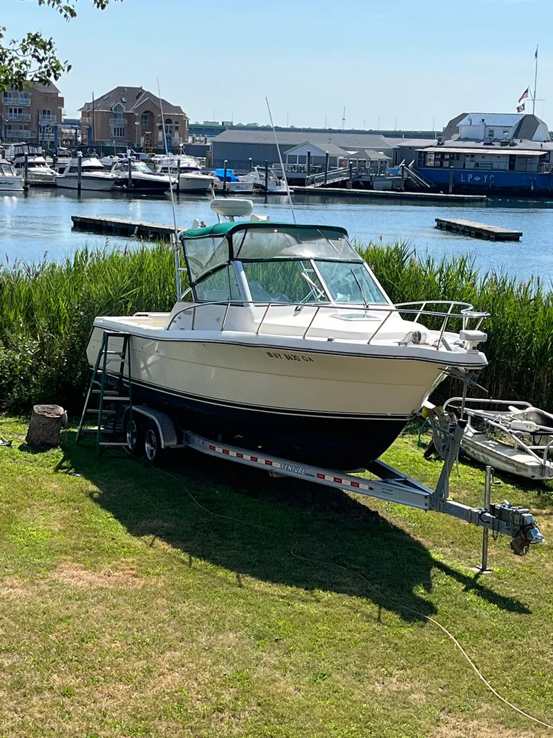Slide: The Image of 2000 Pursuit 2860 Denali boat on trailer by waterfront marina. - 2