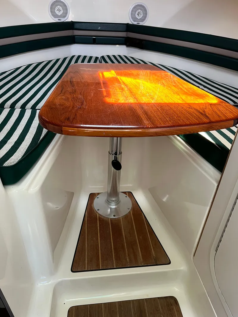 Slide: The Image of 2000 Pursuit 2860 Denali cabin interior with wooden table and striped seating. - 6