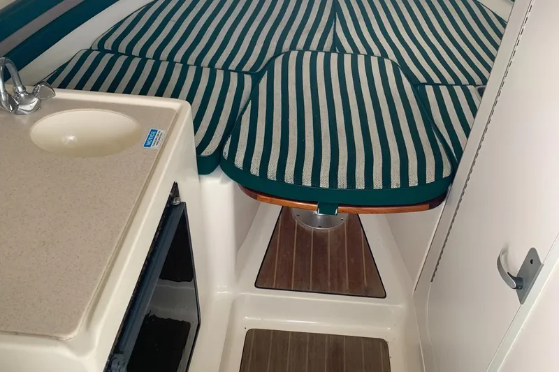 Slide: The Image of 2000 Pursuit 2860 Denali cabin interior with striped cushions and compact sink. - 7