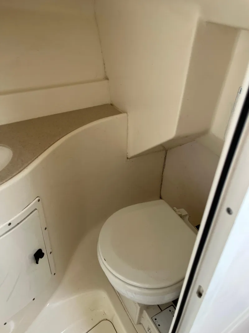 Slide: The Image of 2000 Pursuit 2860 Denali boat bathroom with compact toilet and storage. - 9