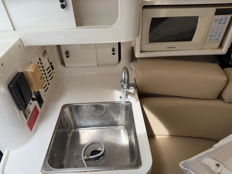 Slide: The Image of Compact boat kitchenette with sink, microwave, and beige seating in a 1999 Intrepid 339 Walkaround. - 15