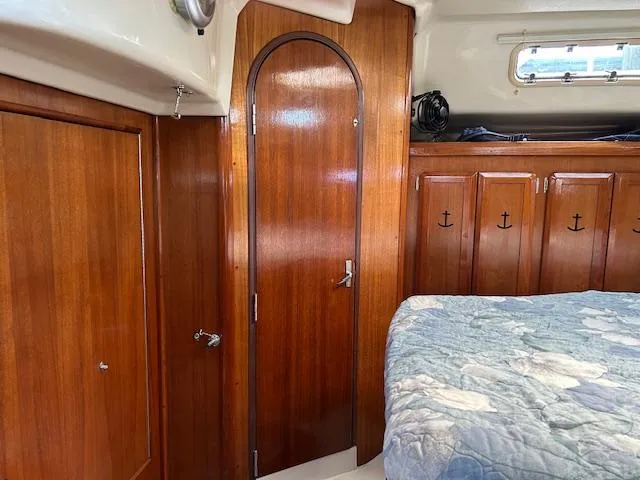 Slide: The Image of Interior of 1993 Hunter Passage 42 sailboat with wooden cabinetry and cozy bedding. - 10