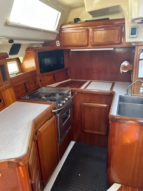 Slide: The Image of 1993 Hunter Passage 42 yacht kitchen with wooden cabinetry, stove, and sink. - 4