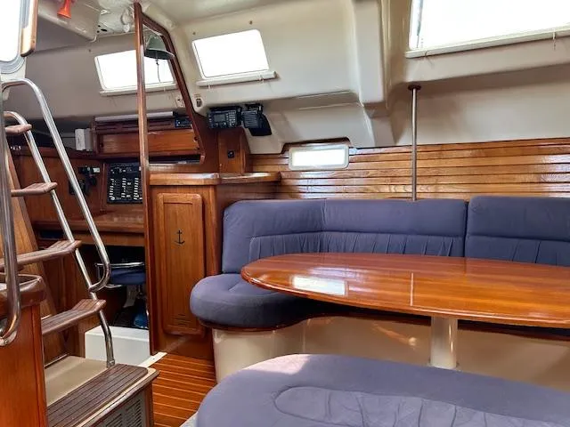 Slide: The Image of Interior of 1993 Hunter Passage 42 sailboat with wooden table and blue seating. - 6