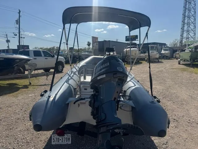 Slide: The Image of 2019 Zodiac Bayrunner 420 inflatable boat with Yamaha outboard motor, parked near a warehouse. - 2