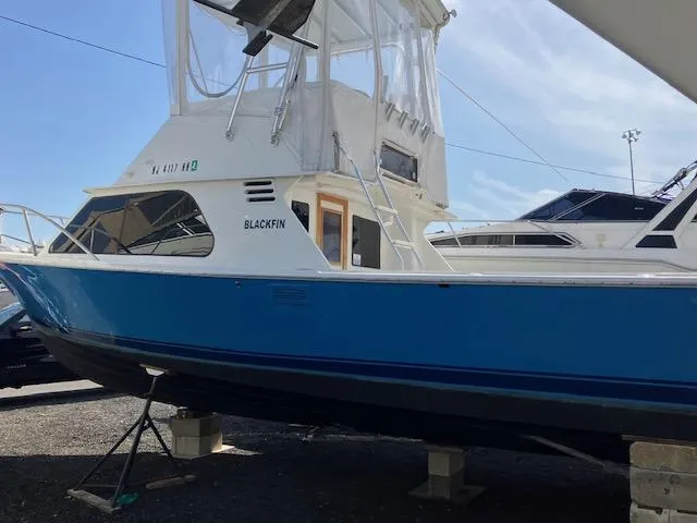 Slide: The Image of 1987 Blackfin 32 Flybridge boat with blue hull, docked on land. - 3
