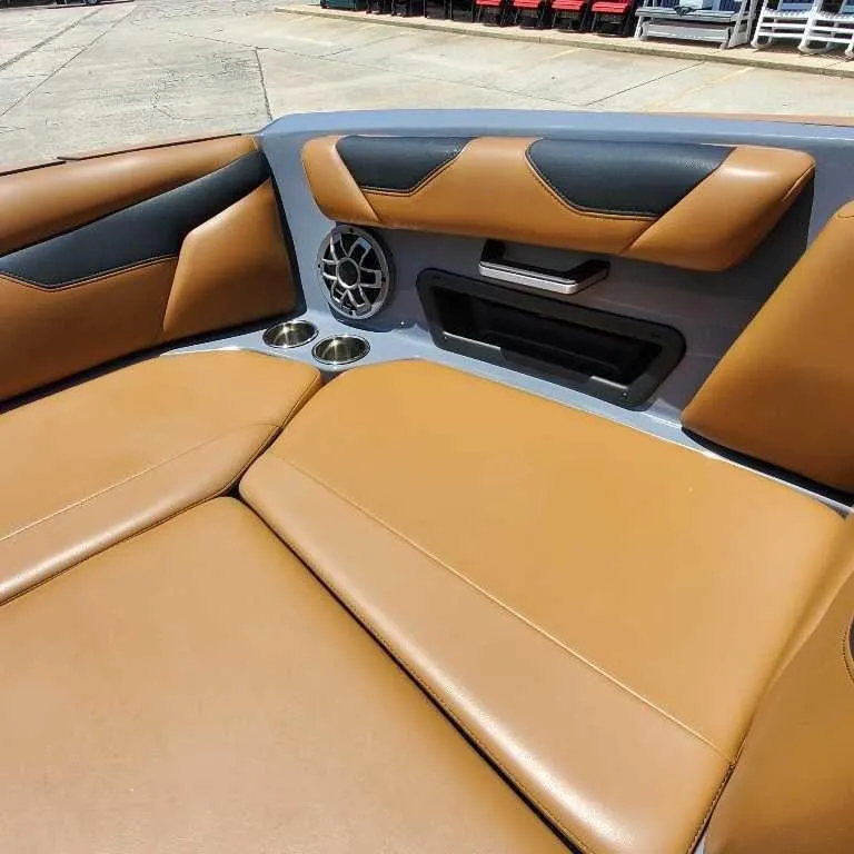 Slide: The Image of 2022 Axis Core Series A22 boat interior with tan and black seating, cup holders, and speaker. - 16