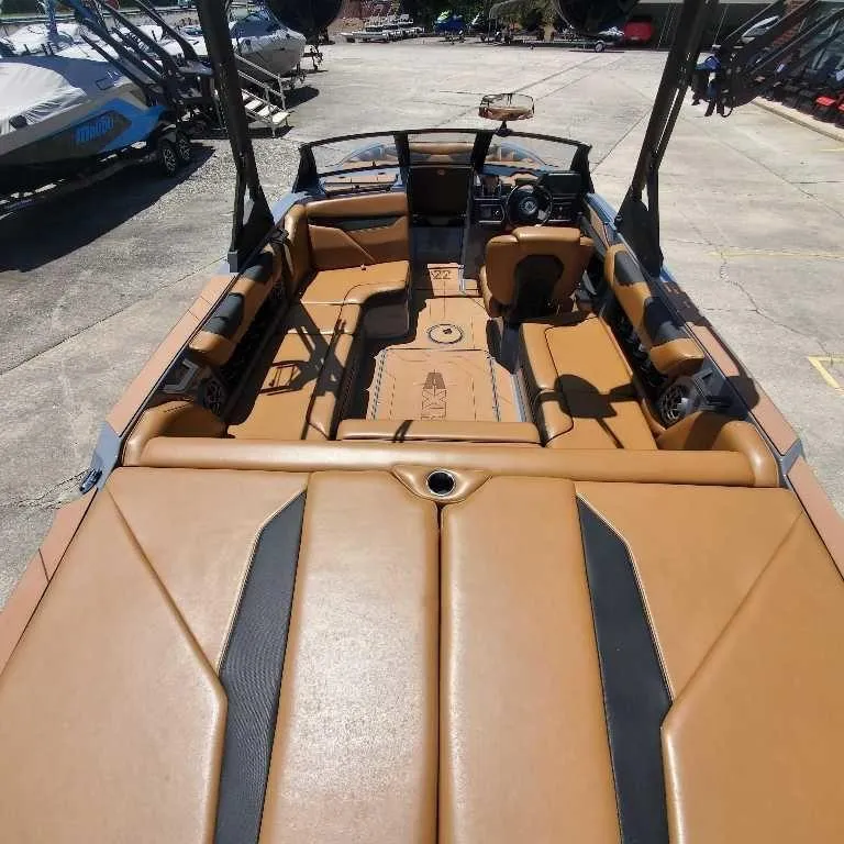 Slide: The Image of 2022 Axis Core Series A22 boat interior with tan and black seating, docked outdoors. - 7