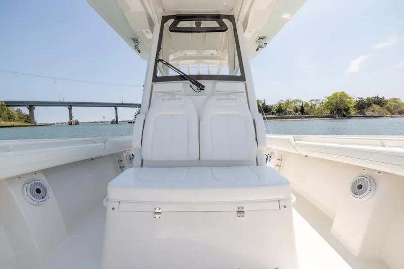 Slide: The Image of 2021 Regulator 28FS boat with dual engines on calm water, bridge and trees in background. - 10